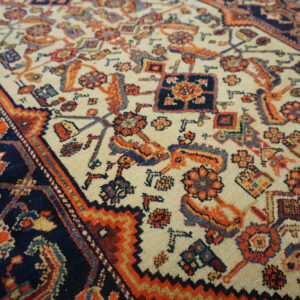 Detailed view of a low pile rug featuring tribal motifs in navy, cream, orange, and red.
