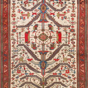 Low-pile rug featuring a complex symmetrical tribal design in red, blue, and brown on an ivory background.