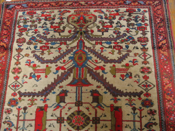 Low-pile rug with a beige field, featuring a central stylized design and geometric motifs in red, blue, and brown.