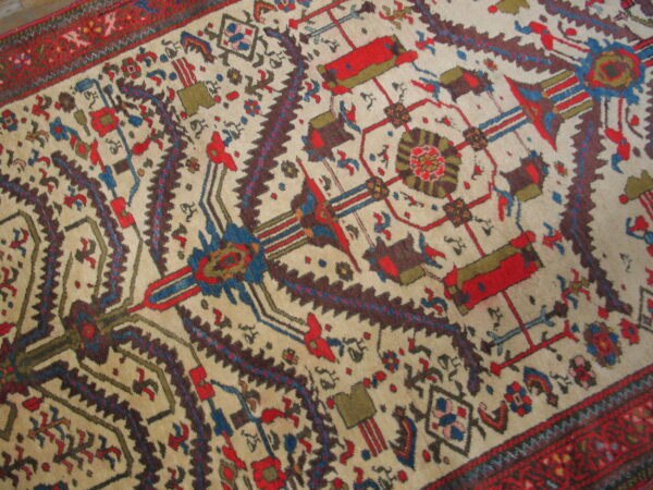 Geometric and stylized motifs in red, navy, brown, and olive green cover the cream-colored rug field.