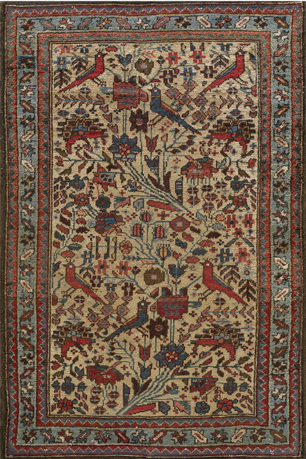 A traditional beige rug features stylized red and blue birds among intricate floral motifs and a dusty blue border.