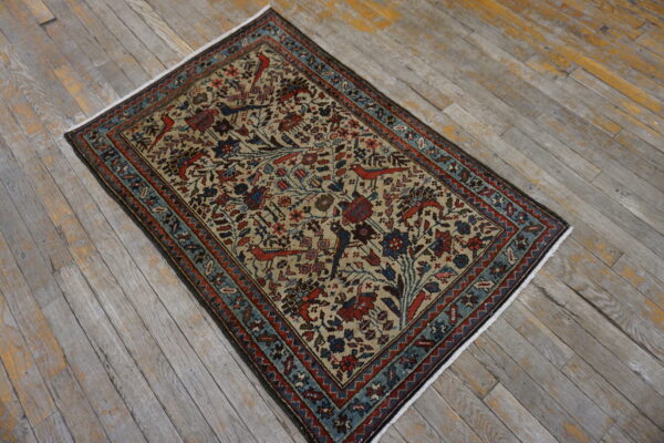 Traditional rug with a beige field, red and blue floral patterns, and bird motifs on distressed gray wood floors.