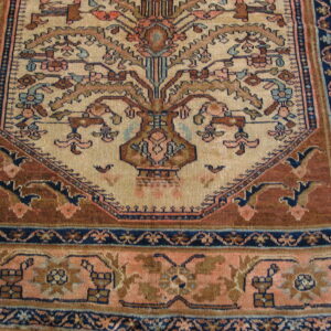 Detailed rug border and field featuring a botanical vase pattern on beige, rust, and navy blue.