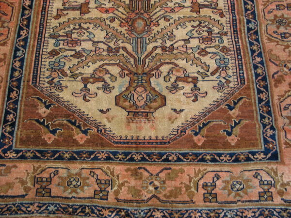Detailed rug border and field featuring a botanical vase pattern on beige, rust, and navy blue.