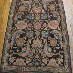 Dark-field runner rug with complex floral and stylized bird designs laid on natural wood planks.