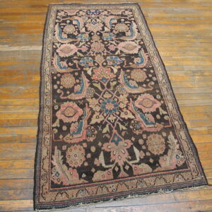 Dark brown runner rug with pink, blue, and beige floral designs sits on a golden hardwood floor.