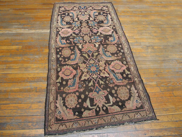 Dark brown runner rug with pink, blue, and beige floral designs sits on a golden hardwood floor.
