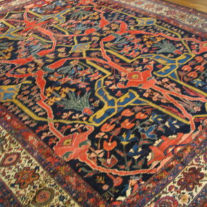 Ornate medium-pile rug featuring red stylized figures and vines on a navy background with thick geometric borders.