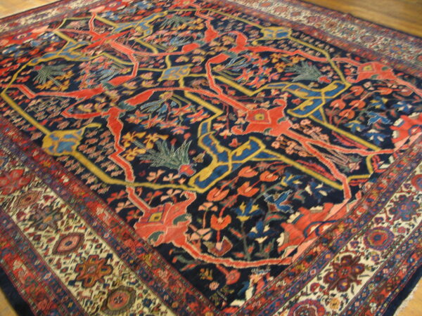 Ornate medium-pile rug featuring red stylized figures and vines on a navy background with thick geometric borders.