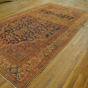 Low-pile rug in rich orange and blue traditional patterns on distressed wooden planks.