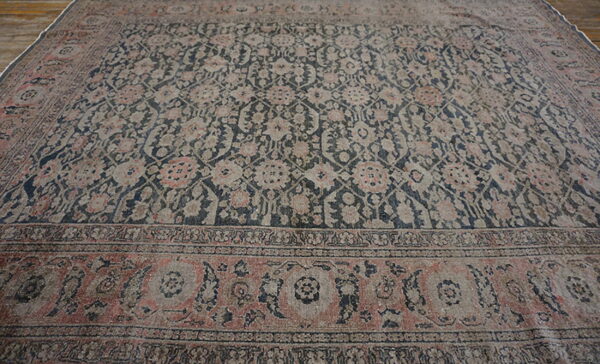 Faded area rug featuring a dense navy and gray floral pattern with terracotta accents on wood floor.