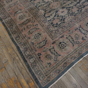Low pile traditional rug with blue and rose floral border on weathered plank wood flooring.