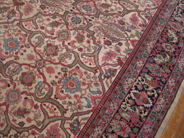 Detailed low-pile rug featuring a cream floral field and a contrasting navy border on wood floor.