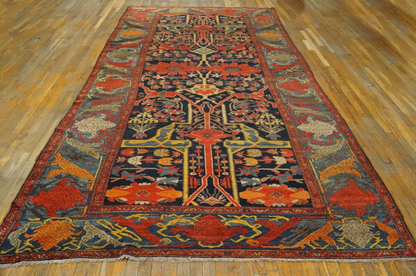 Long, low-pile rug with a complex navy, red, and yellow traditional design centered on a wood plank floor.