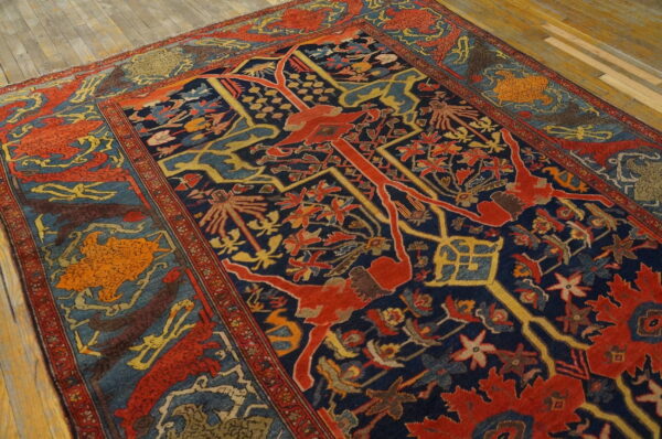 A traditional rug features a navy blue field with complex red, yellow, and blue patterns on light wooden floors.