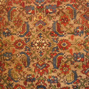 Traditional high-pile rug detail with a tan field and red, blue, yellow, and green floral geometric motifs.