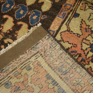 Close-up of multiple rugs showing dark brown and coral patterns, woven backs, and a taped selvedge edge.