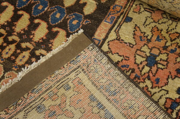 Close-up of multiple rugs showing dark brown and coral patterns, woven backs, and a taped selvedge edge.