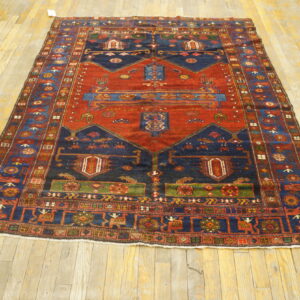 Rust and navy geometric rug with multiple borders displayed on light wood plank flooring.