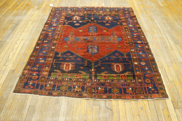 Rust and navy geometric rug with multiple borders displayed on light wood plank flooring.