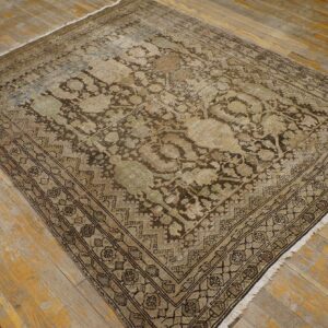 Distressed traditional rug in faded tan, brown, and green rests on rustic wooden plank flooring.