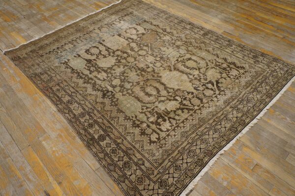 Distressed traditional rug in faded tan, brown, and green rests on rustic wooden plank flooring.