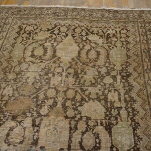 Heavily distressed low-pile rug with faded brown and sage traditional motifs on a rustic wood floor.