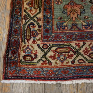 Low-pile rug with intricate teal, red, and cream patterns rests on rustic gray wood planks.