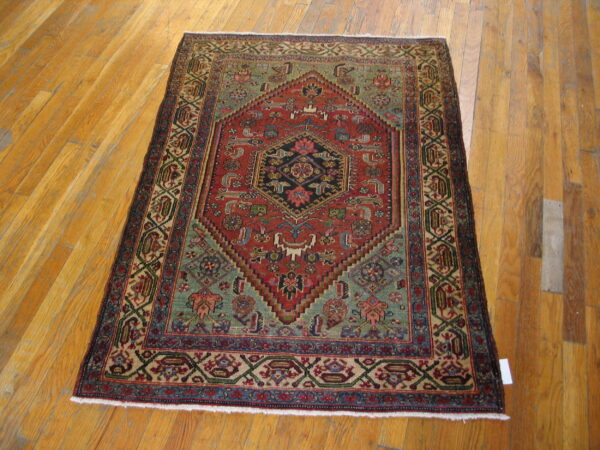 Geometric red rug with blue and teal highlights features a central medallion on light wood flooring.