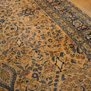 Ornate gold rug with dense blue and pink floral patterns borders visible on light wood flooring.