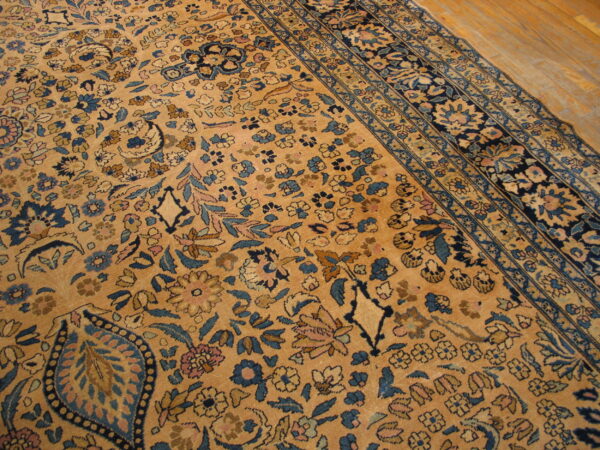 Ornate gold rug with dense blue and pink floral patterns borders visible on light wood flooring.