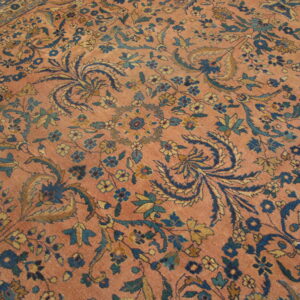 Low-pile rug with a coral field and a dense all-over pattern of blue, teal, and gold florals.