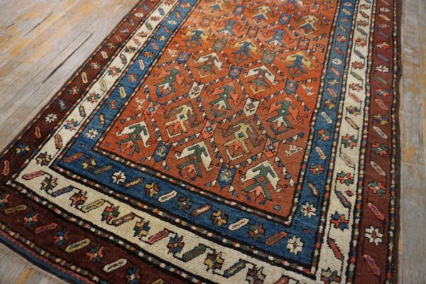 A rust and blue geometric rug with tribal motifs rests on distressed wooden floorboards.