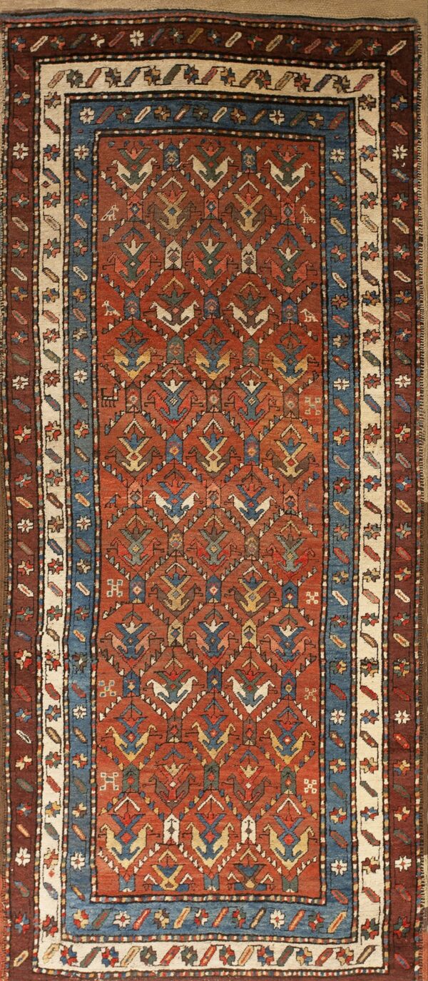 Terracotta runner with repeating geometric bird motifs and multi-layered borders in blue, cream, and brown.