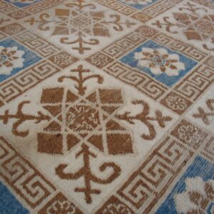 Off-white rug with a geometric grid pattern in rust brown and bright blue floral squares.