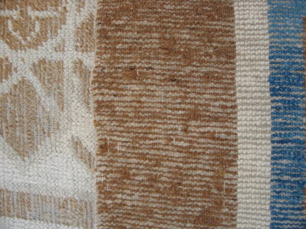 Close weave showing chunky white, brown, and blue vertical stripes next to a tan patterned section.