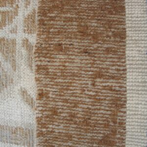 Textured rug detail displaying a cream and brown pattern next to vertical stripes of brown, cream, and blue.