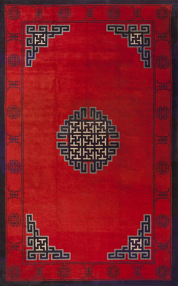 A red rug with a central fretwork medallion and geometric borders in navy blue and off-white accents.