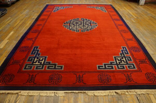 Bright red rug with a complex blue, grey, and cream geometric pattern on wood flooring.