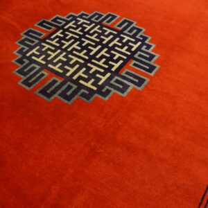 Red rug with a large geometric medallion pattern in navy blue, light blue, and beige.