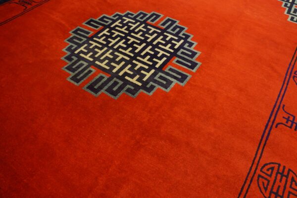 Red rug with a large geometric medallion pattern in navy blue, light blue, and beige.