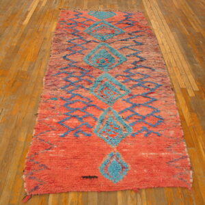 Shaggy coral and turquoise runner with large diamond motifs rests on plank hardwood flooring.