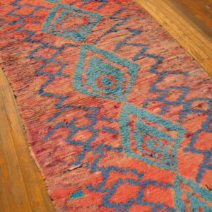 High-pile pink and turquoise rug runner featuring geometric designs on light wood flooring.