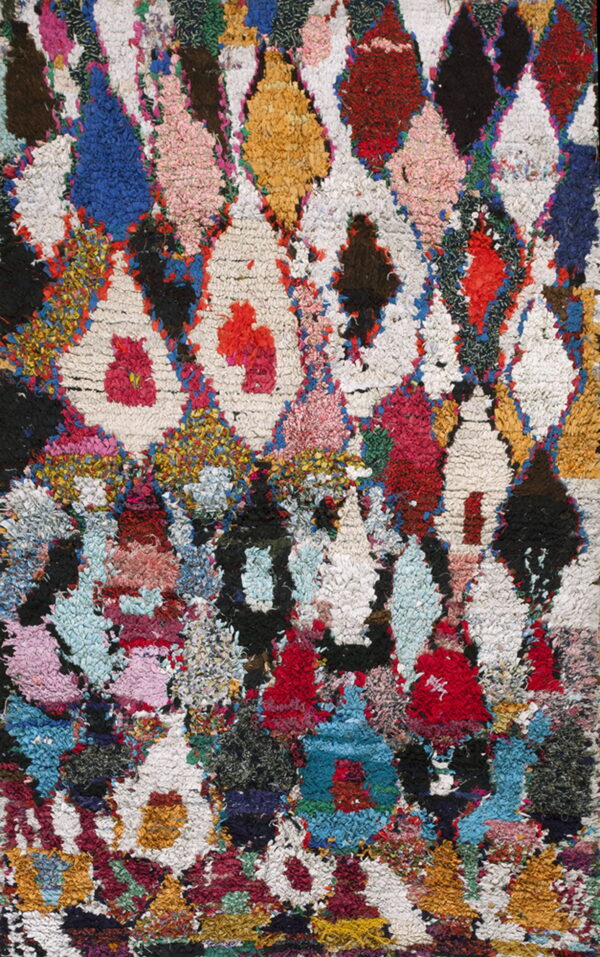 High-pile, shaggy rug with a multicolor geometric diamond pattern in red, blue, yellow, pink, and white.