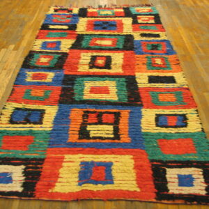 High-pile runner rug with vibrant geometric blocks in red, blue, green, yellow, and black on wood floor.