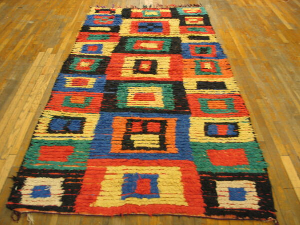 High-pile runner rug with vibrant geometric blocks in red, blue, green, yellow, and black on wood floor.