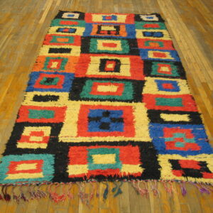High-pile runner rug with vibrant blocks of red, blue, yellow, and black on hardwood flooring.