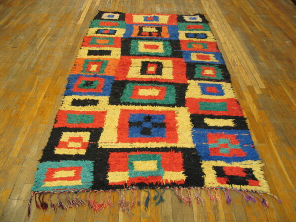 High-pile runner rug with vibrant blocks of red, blue, yellow, and black on hardwood flooring.