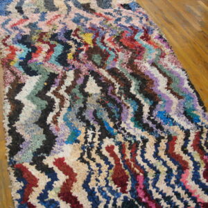 Multicolor zigzag stripes decorate a textured, shaggy runner placed on a polished wood floor.
