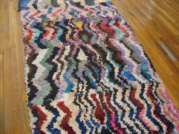 Multicolor zigzag stripes decorate a textured, shaggy runner placed on a polished wood floor.